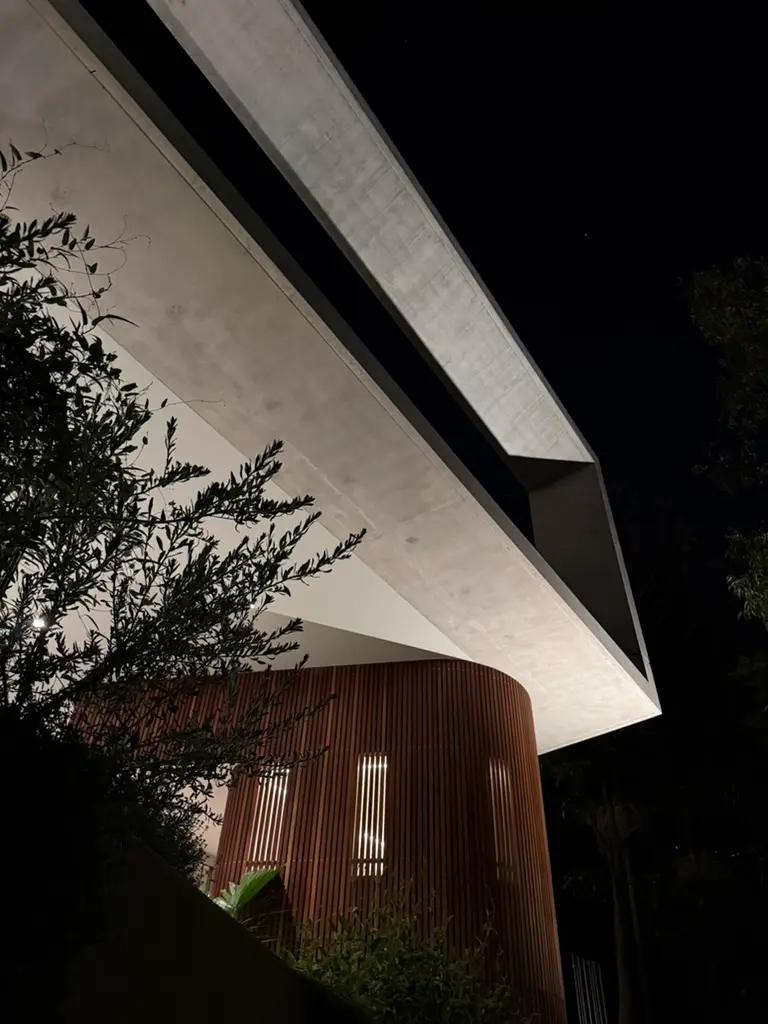 Off-form concrete overhang above curved timber battens and planting at the Northbridge residence