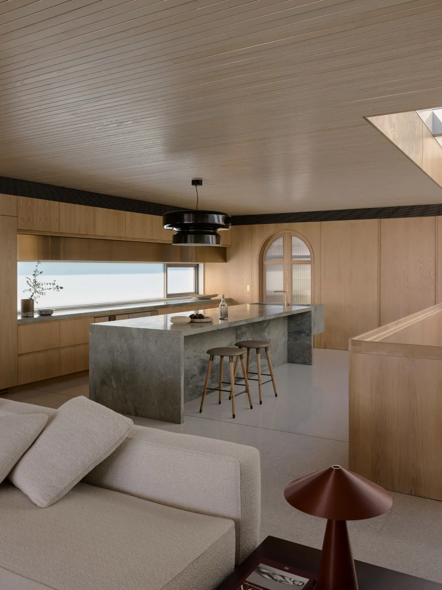 Oak and stone kitchen with a long island, concealed lighting and slot window to the sea
