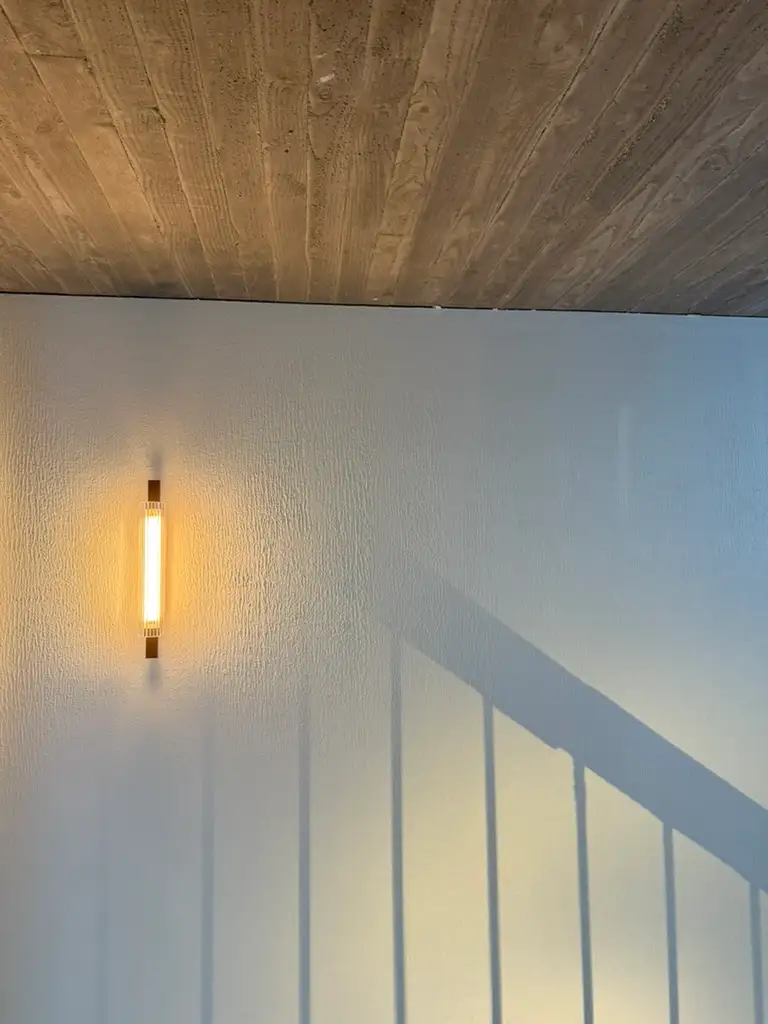 Stair with a white balustrade, wall light and exposed concrete ceiling