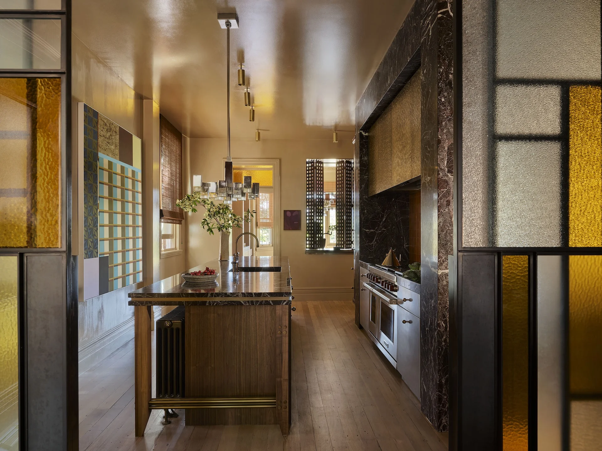 Galley kitchen with marble surrounds, brass track lighting and stained glass screens