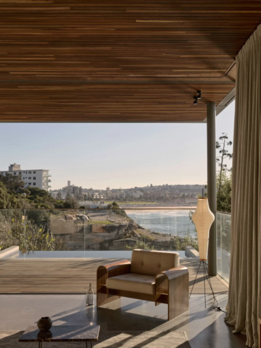 Terrace with timber soffit, pool edge and Bondi beach beyond, sheer curtains drawn back