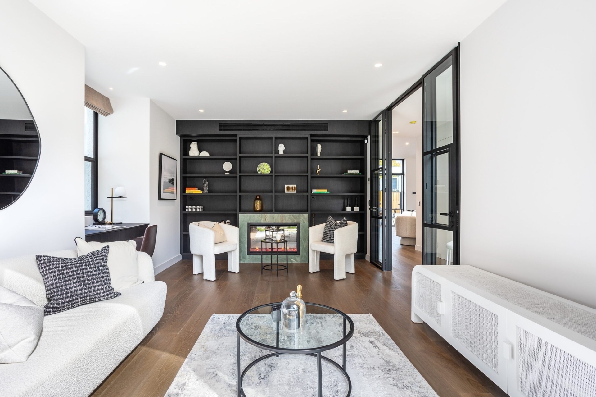 Sitting room with black joinery, fireplace and a wall keypad beside the glazed doors