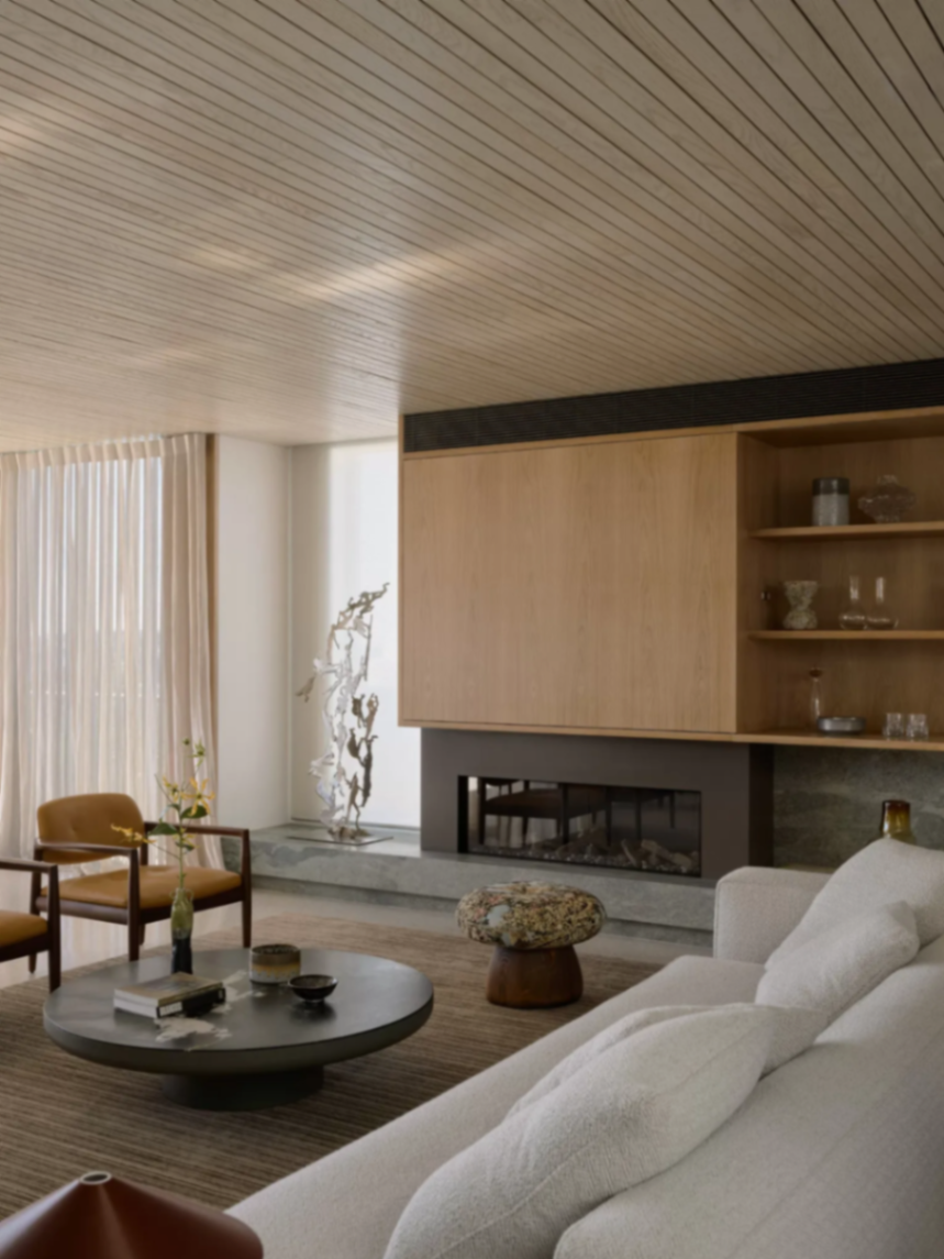 Living room fireplace with oak joinery concealing a television and sheer motorised curtains