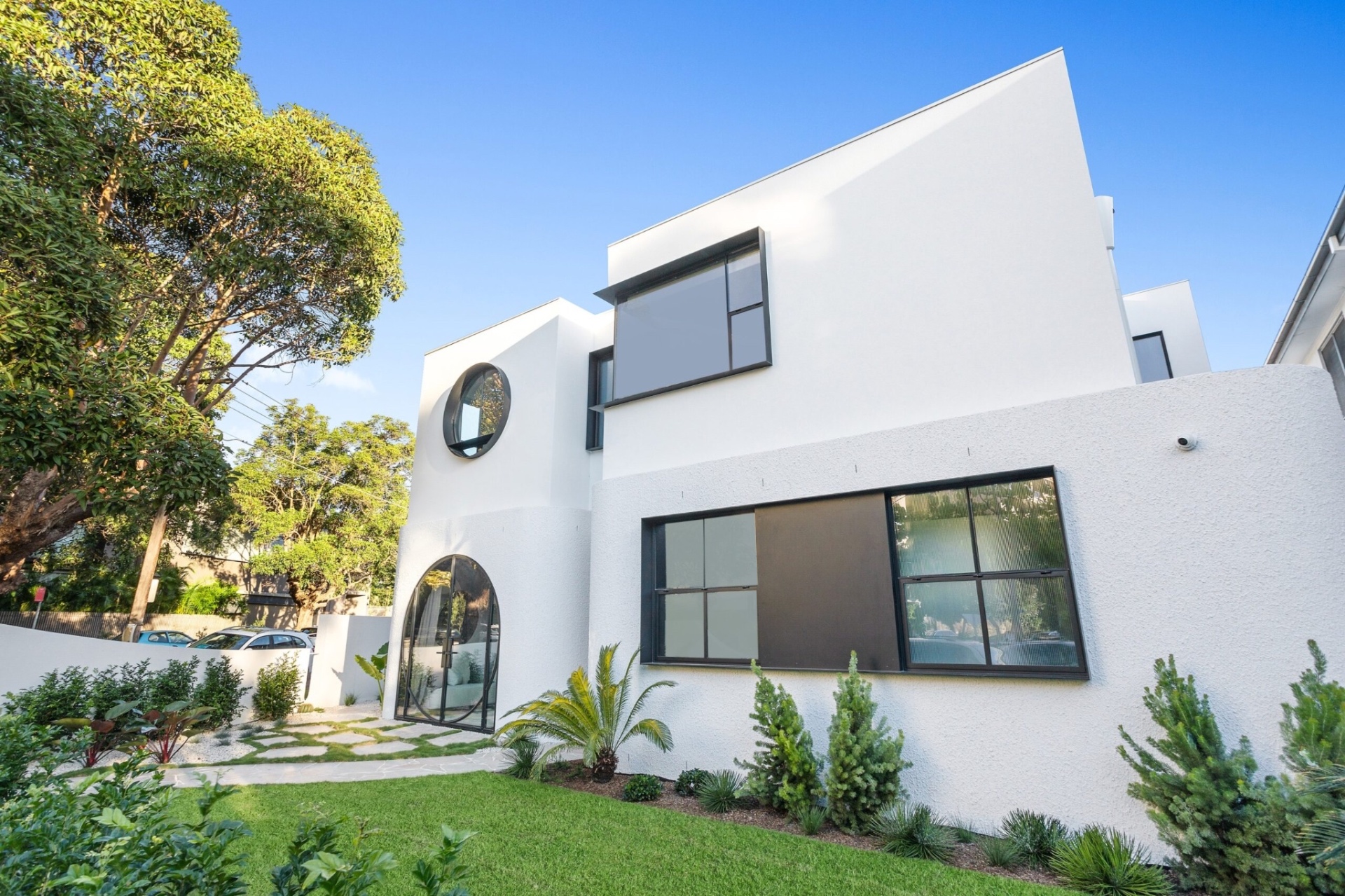White modernist Double Bay residence with curved forms, circular window and arched glazed entry