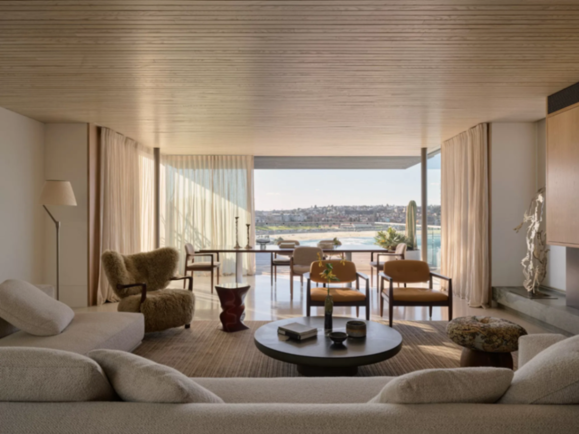 Open living and dining room with timber lined ceiling and full width ocean outlook at Bondi