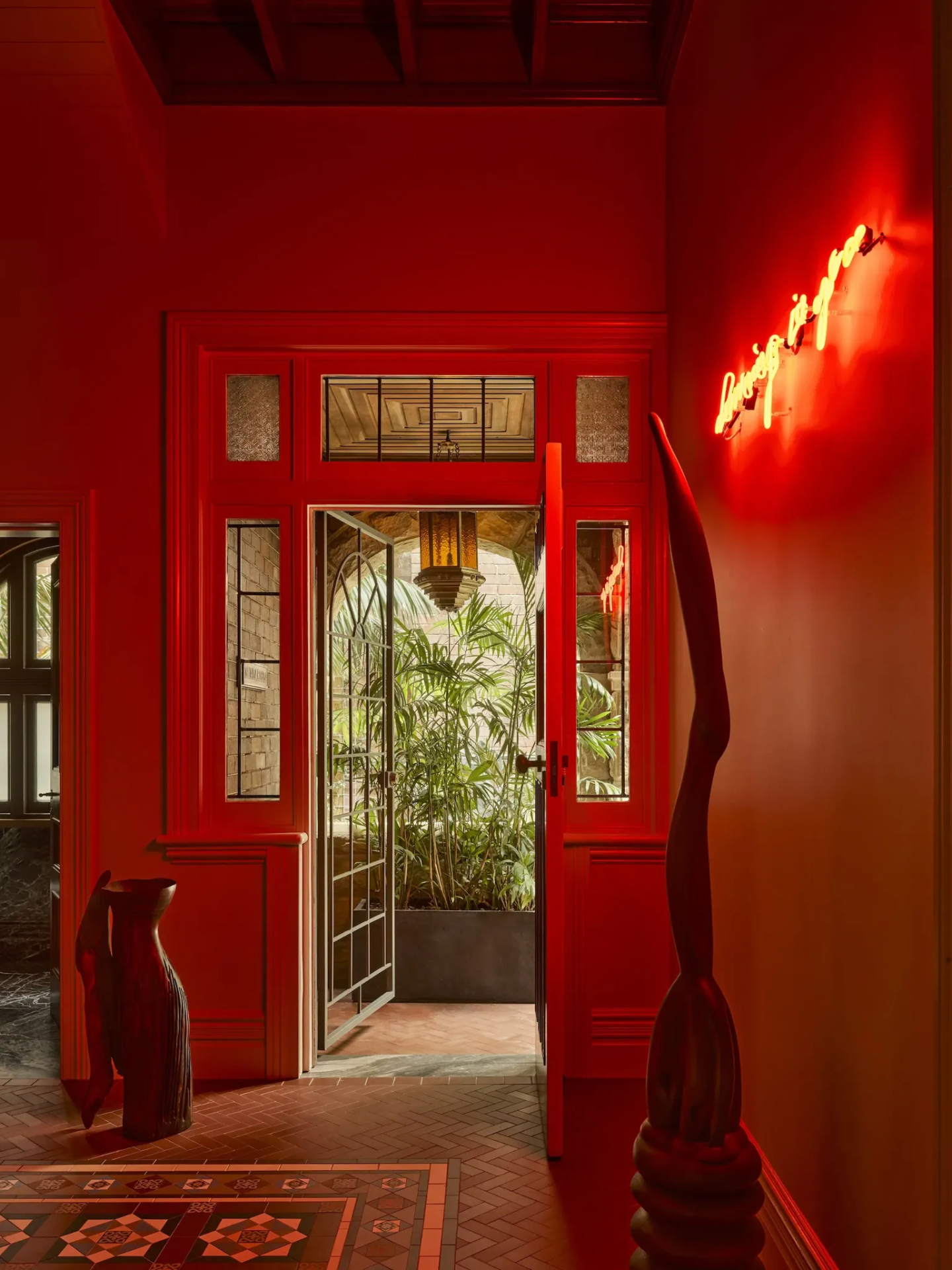 Deep red heritage entry hall with tessellated tiling, timber joinery and a neon artwork