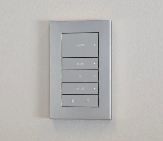 Brushed silver Control4 Lux keypad installed on a pale wall with engraved scene names