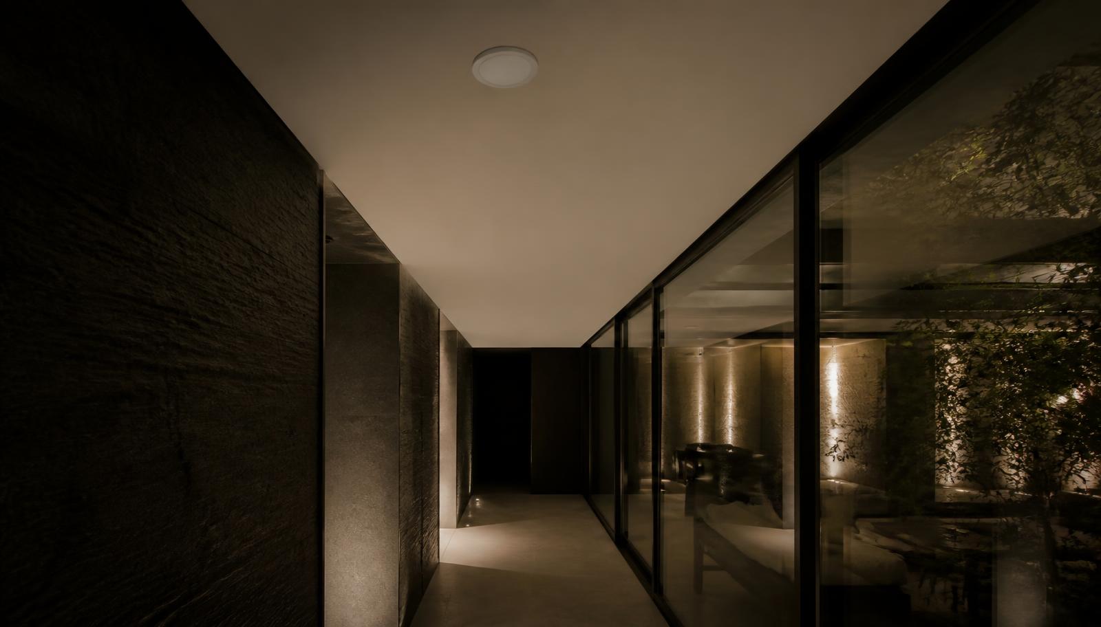 Dark stone and glass hallway of a luxury home at night with a single discreet ceiling-mounted access point providing coverage