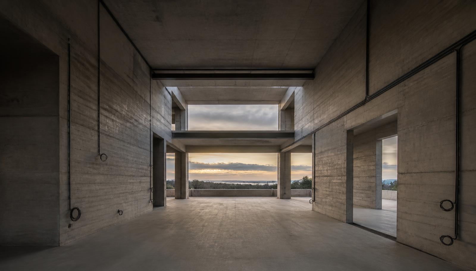Off-form concrete shell of a luxury Sydney home at rough-in stage, conduit runs waiting for cabling